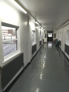 Corridor lighting for a hospital upper floor with mixed natural and LED lighting.